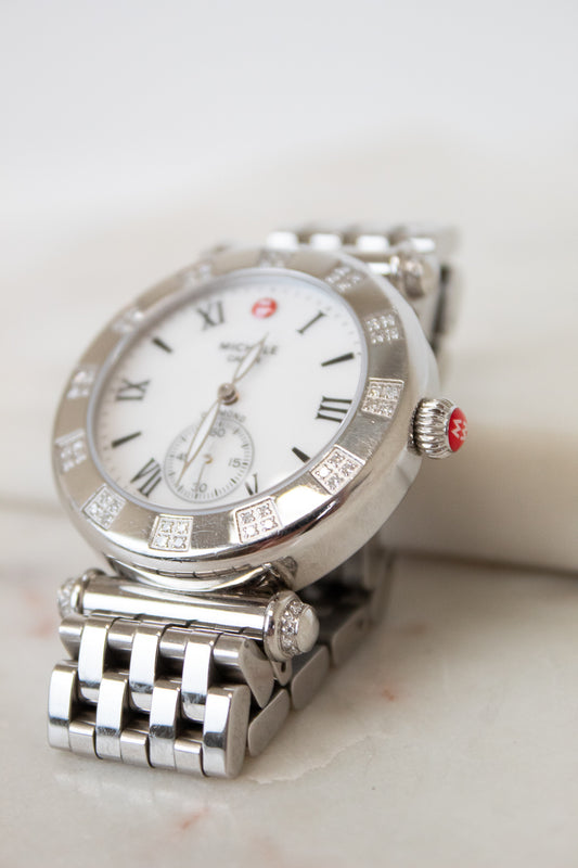 Silver watch with a white face on a light background