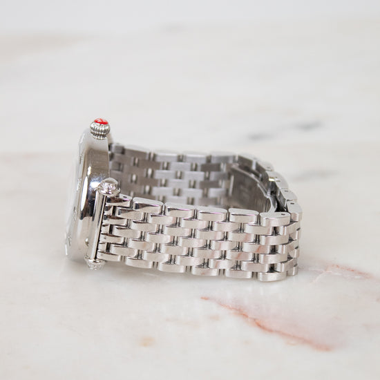 Silver watch with a woven metal strap on a light marble background