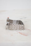 Silver watch with a woven metal strap on a light marble background