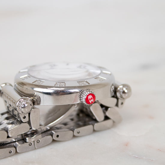 Silver watch with a red logo on a marble surface