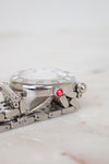 Silver watch with a red logo on a marble surface