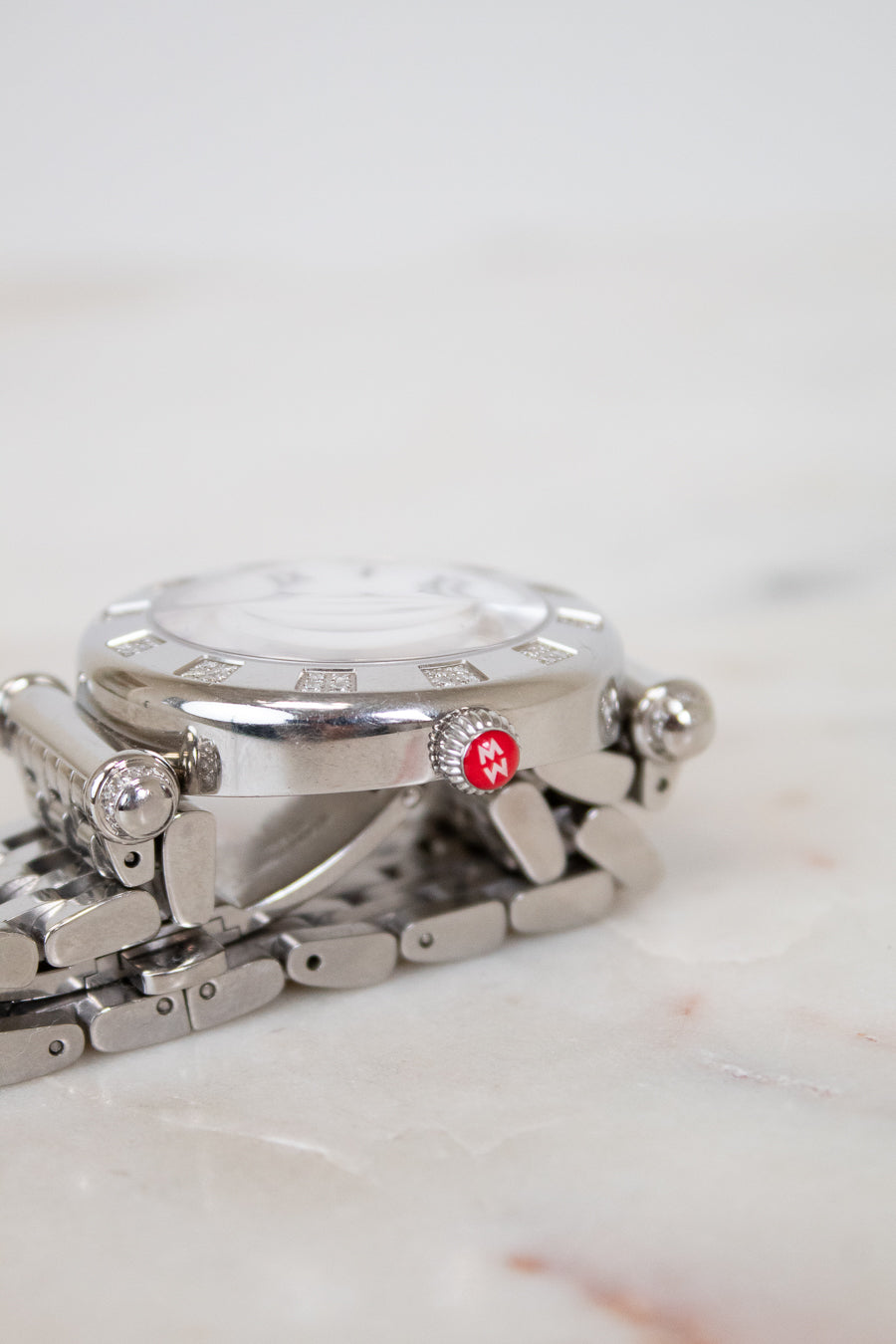 Silver watch with a red logo on a marble surface