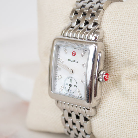 Silver Michele watch on a white cushion with a light background