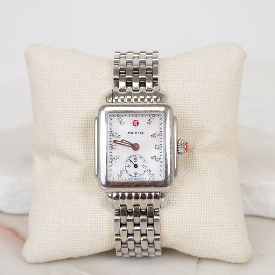 Silver watch with a detailed face on a white cushion