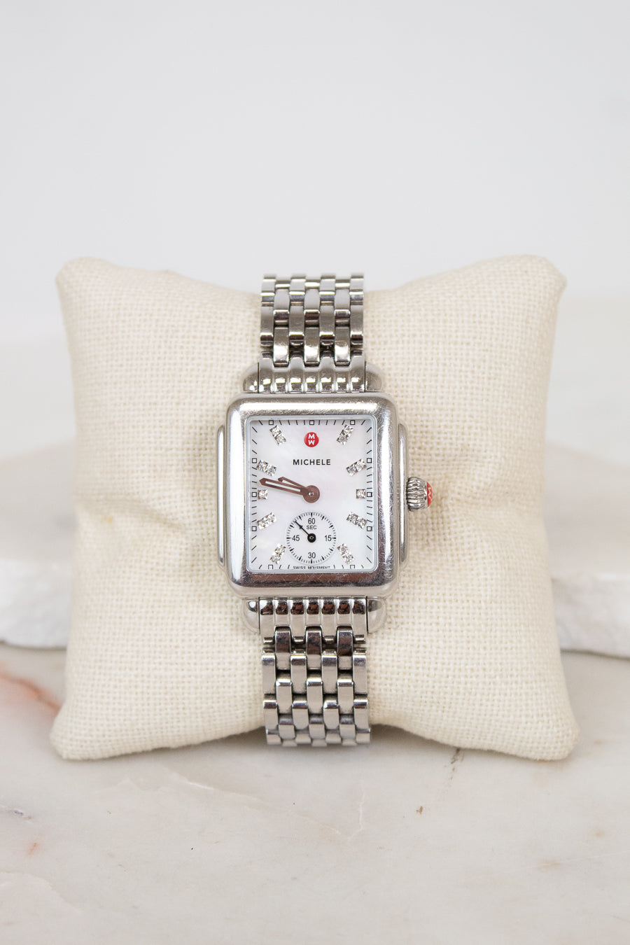 Silver watch with a detailed face on a white cushion