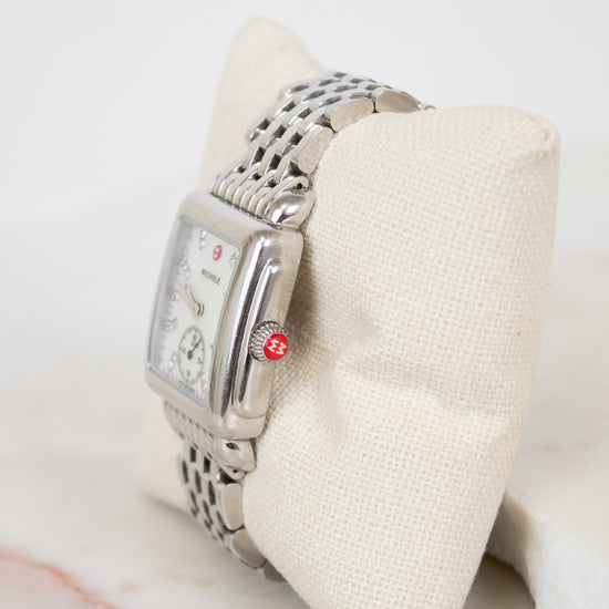 Silver watch on a white cushion with a marble surface