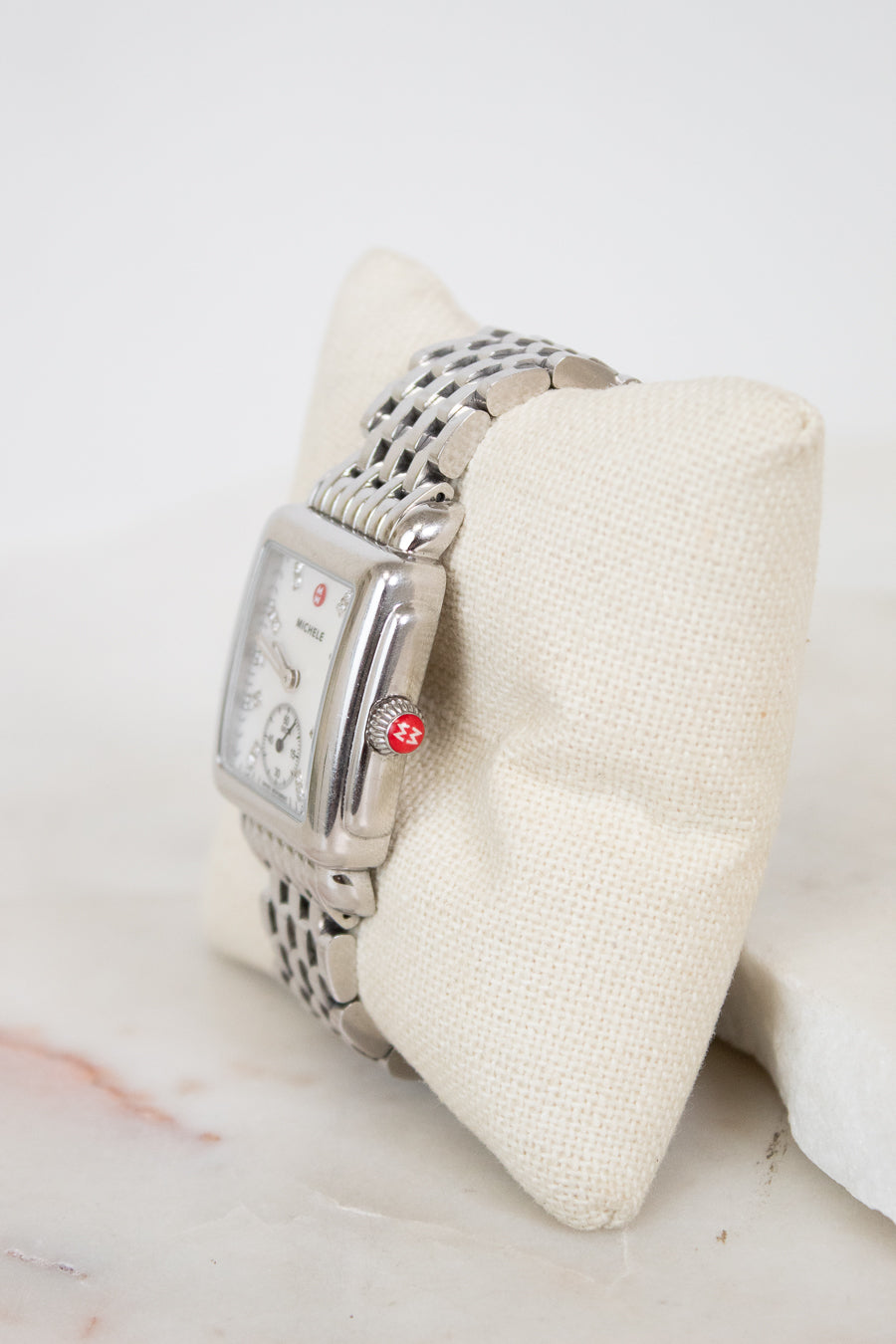 Silver watch on a white cushion with a marble surface
