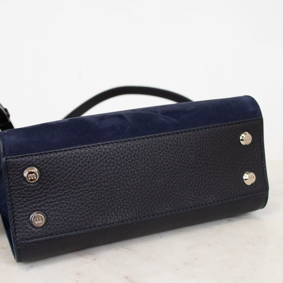 Black leather handbag with silver-tone feet on a marble surface