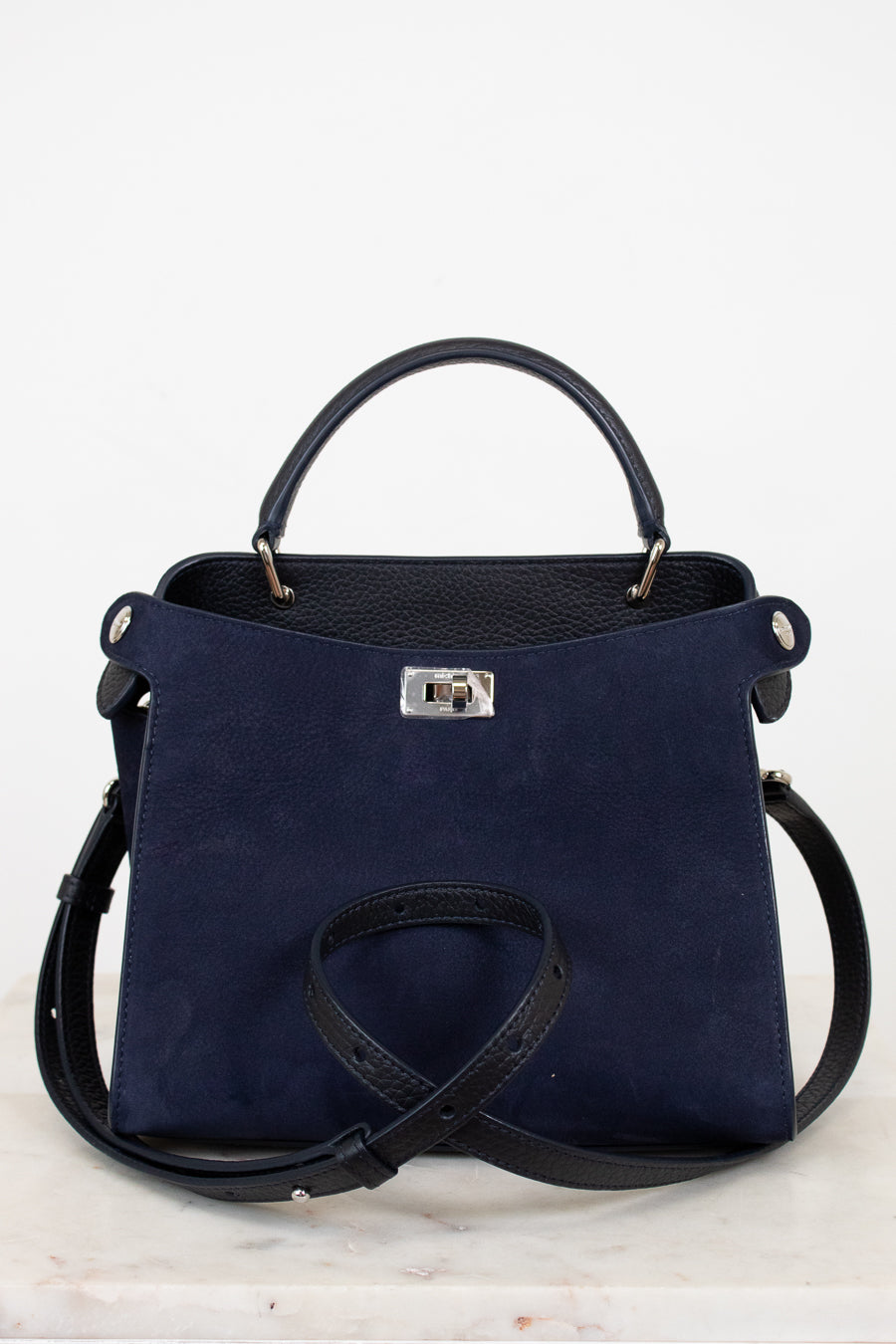 Navy blue handbag with silver-tone accents on a light gray background