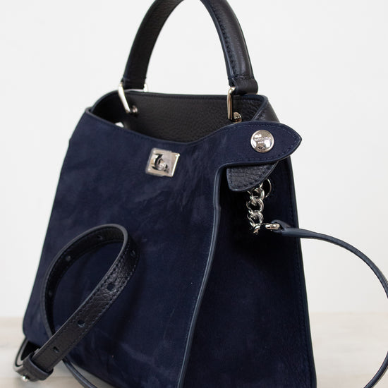 Navy blue handbag with silver-tone accents on a light gray background