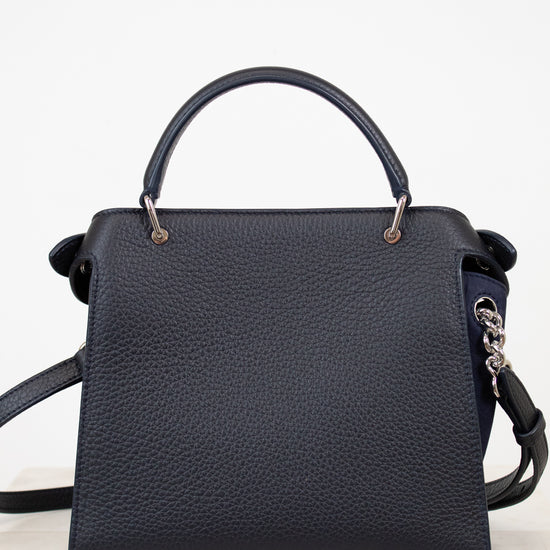 Navy handbag with a strap on a white background