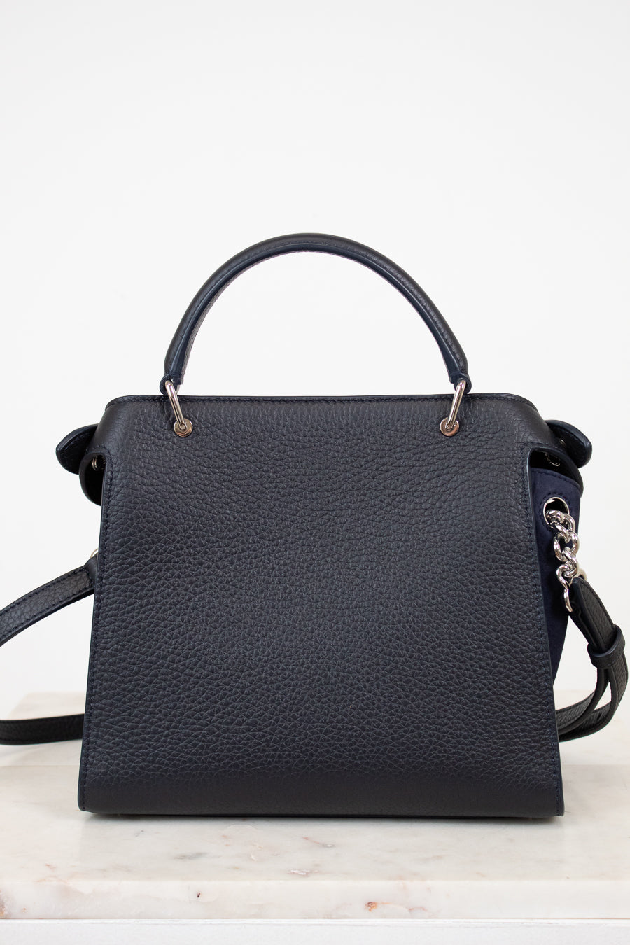 Navy handbag with a strap on a white background