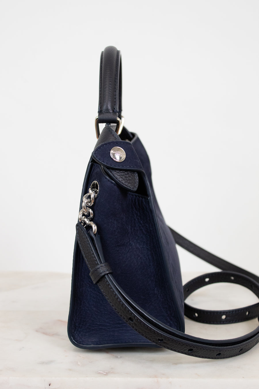 Navy leather handbag with a strap on a light background