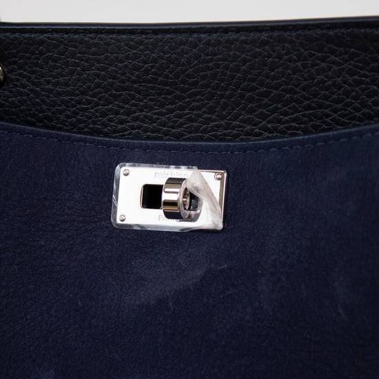 Close-up of a navy blue handbag with a silver clasp on a white background