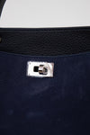 Close-up of a navy blue handbag with a silver clasp on a white background