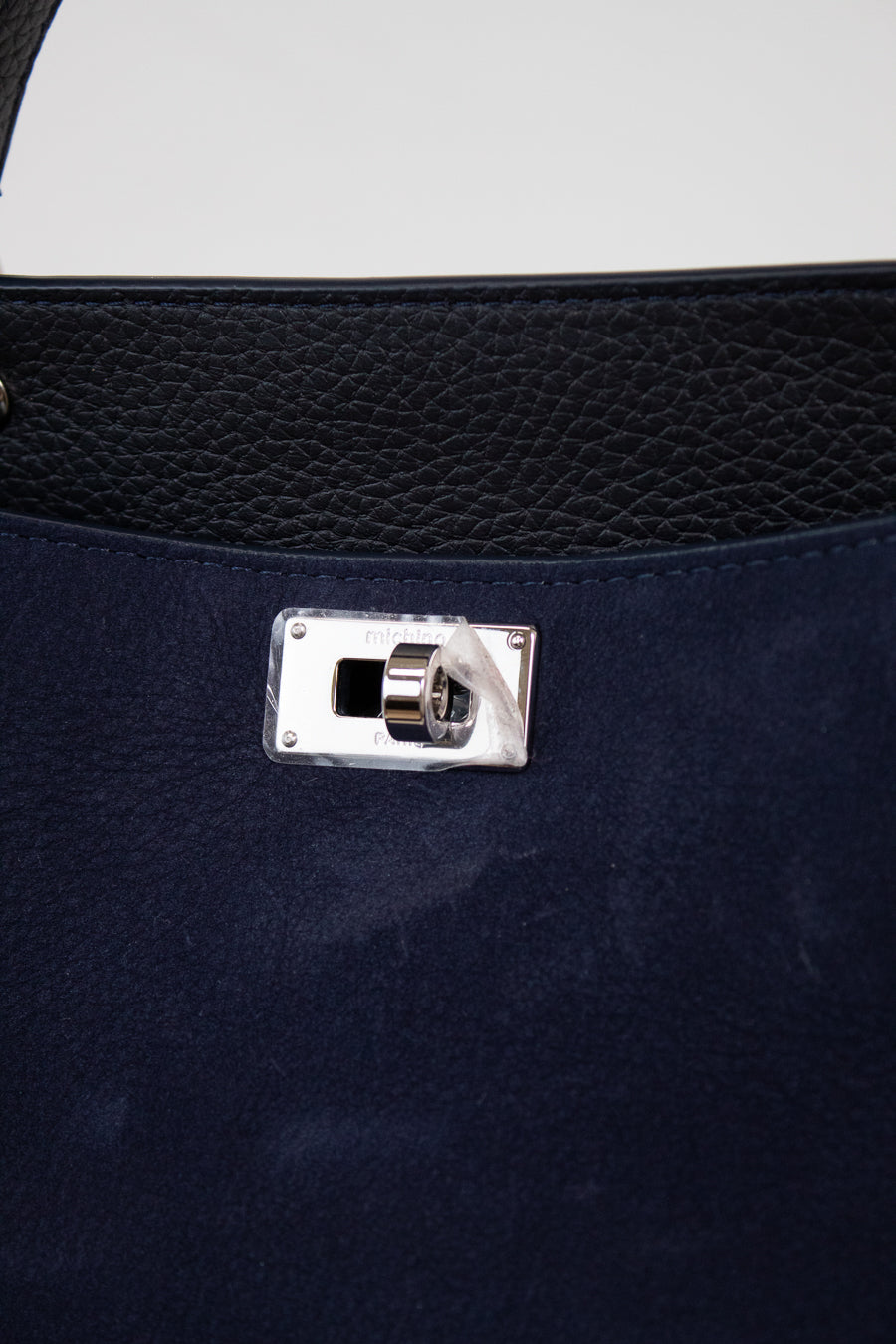 Close-up of a navy blue handbag with a silver clasp on a white background