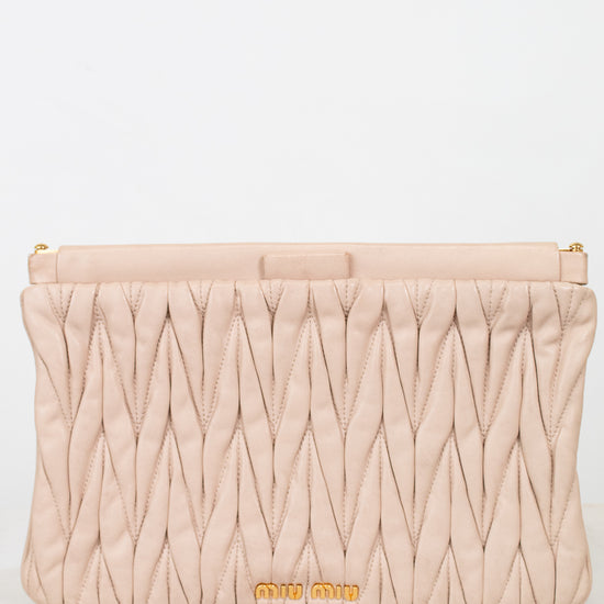 Quilted beige clutch bag with gold logo on a light gray background