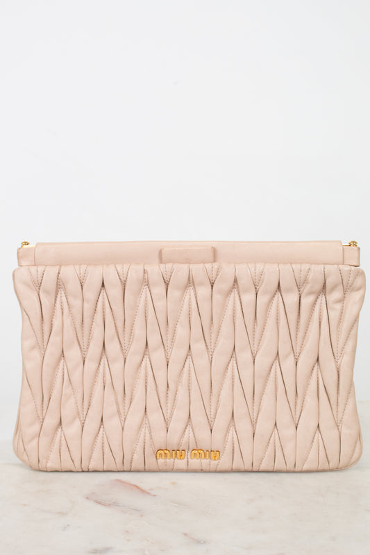Quilted beige clutch bag with gold logo on a light gray background