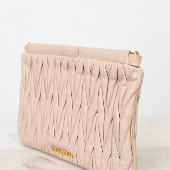 Beige clutch bag with textured pattern and 'miu miu' branding on a light background