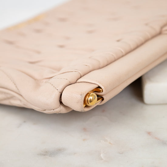 Beige quilted handbag with gold clasp on a marble surface