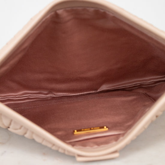 Close-up of a beige handbag with a gold tag on a light background