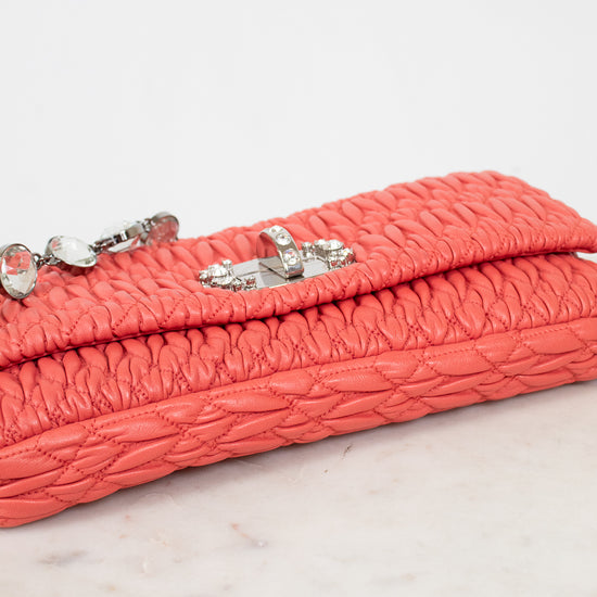 Coral hand bag with decorative clasp on a marble surface