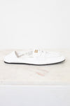 A single white leather Miu Miu loafer flat shoe with gold branding on the side, resting on a white marble surface against a white background.