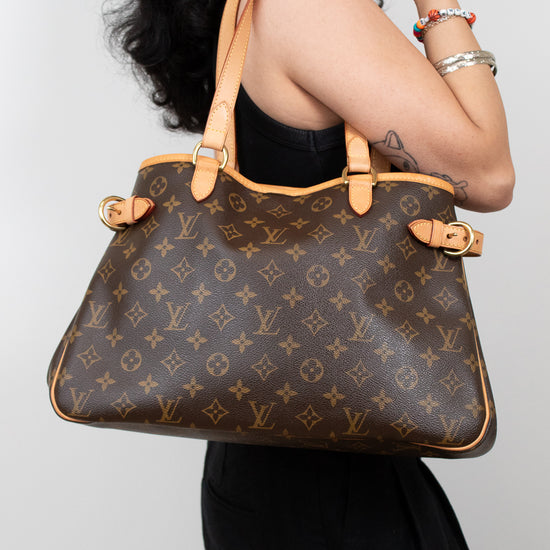 Person holding a Louis Vuitton handbag against a plain background