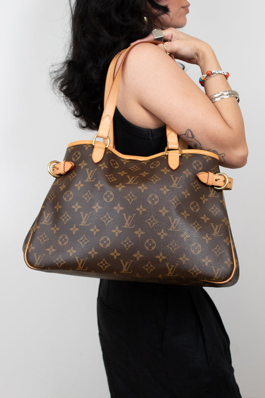 Person holding a Louis Vuitton handbag against a plain background