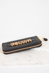 Black wallet with gold zipper and 'Moschino' branding on a white background