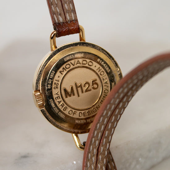 Close-up of a Movado watch with brown leather strap on a marble surface