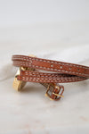Brown leather watch strap with gold clasp on a marble surface