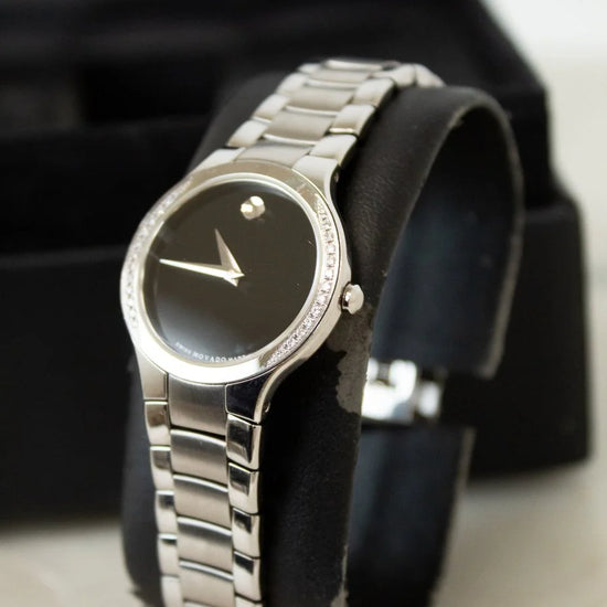 Silver wristwatch on a black cushion with a marble surface background
