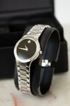 Silver wristwatch on a black cushion with a marble surface background