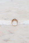 Gold ring with green stones on a marble surface