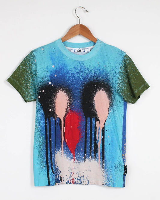 T-shirt with artistic design of three abstract figures and a red heart on a hanger against a white background