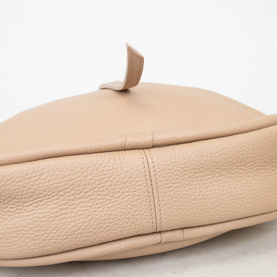 Beige leather handbag on a marble surface with a white background