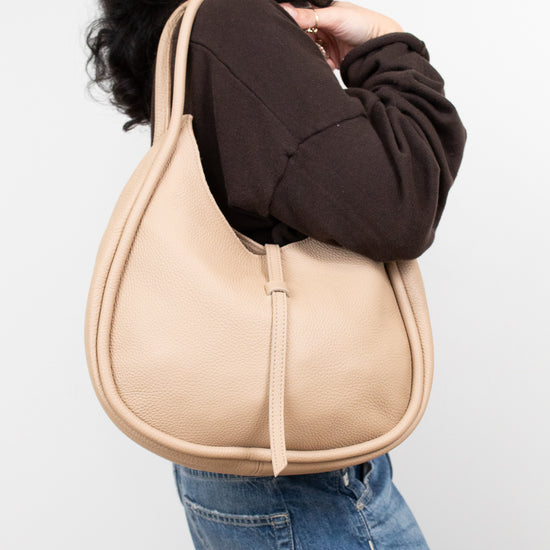 Person wearing a beige shoulder bag against a white background