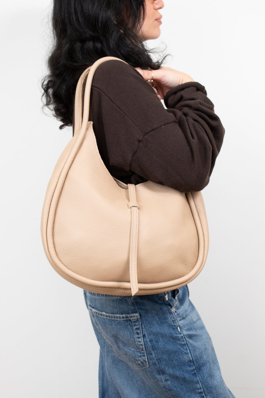 Person wearing a beige shoulder bag against a white background