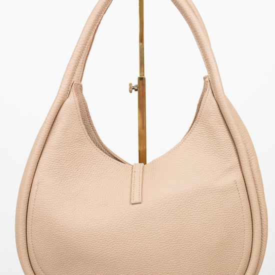 Beige handbag sitting on a gold purse stand on a white background