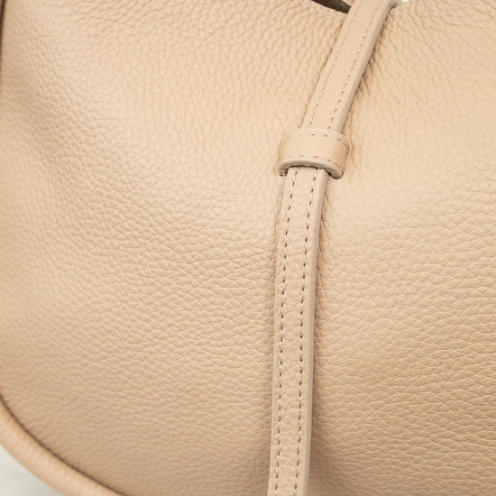 Close-up of a beige leather handbag with a strap on a light background