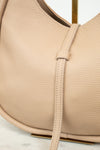 Close-up of a beige leather handbag with a strap on a light background