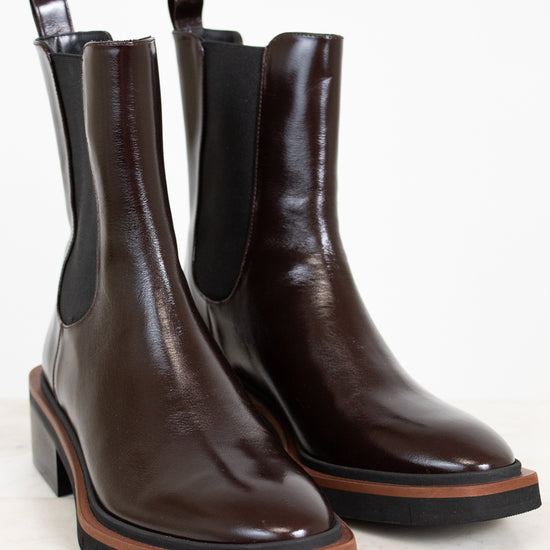 Pair of brown leather Chelsea boots with black elastic sides on a light background
