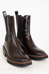 Pair of brown leather Chelsea boots with black elastic sides on a light background