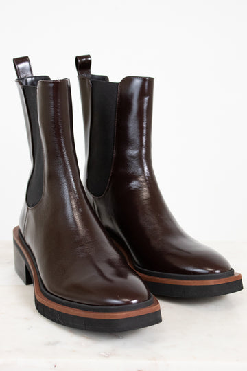 Pair of brown leather Chelsea boots with black elastic sides on a light background