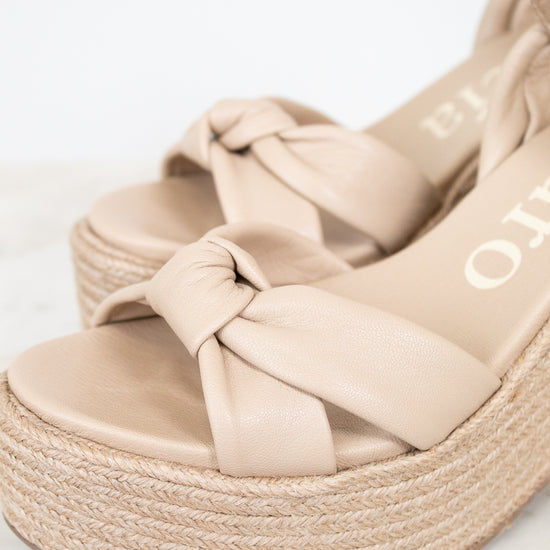 Beige sandal with woven sole on a light background