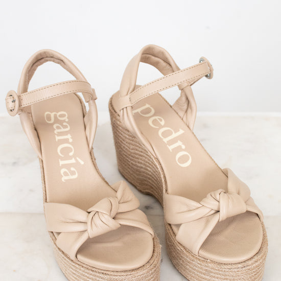 Beige sandals with bow detail on a light background