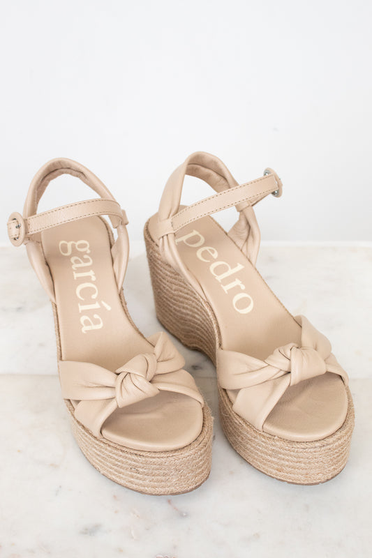 Beige sandals with bow detail on a light background