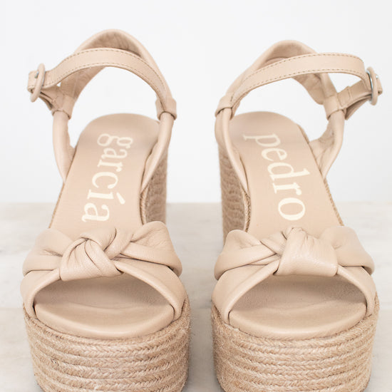 Pair of beige sandals with platform sole on a white background