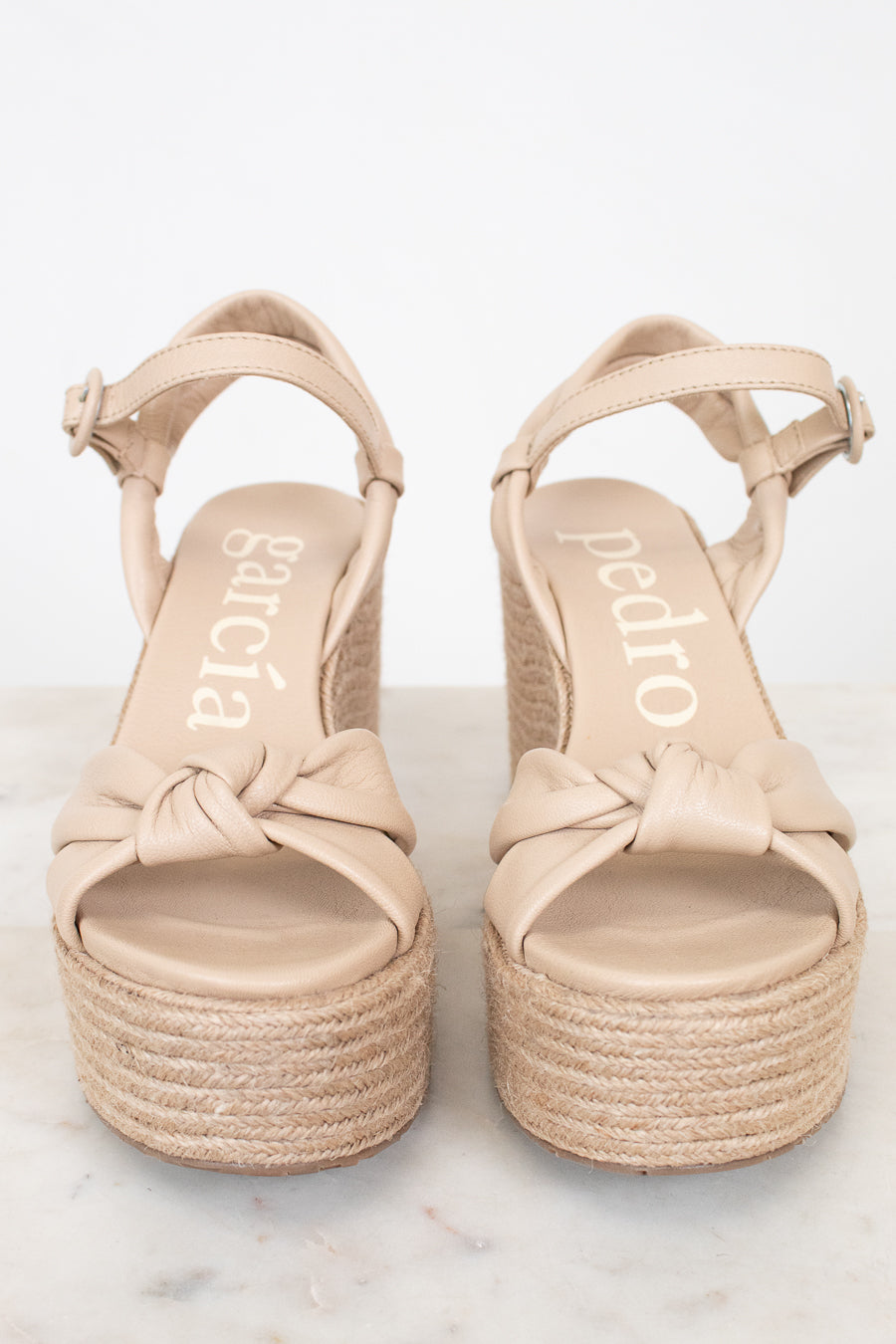 Pair of beige sandals with platform sole on a white background